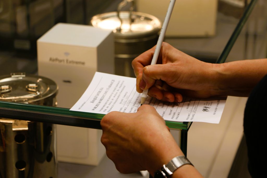 Osoba wypełnia formularz na szklanej ladzie. Person filling out a form on a glass counter